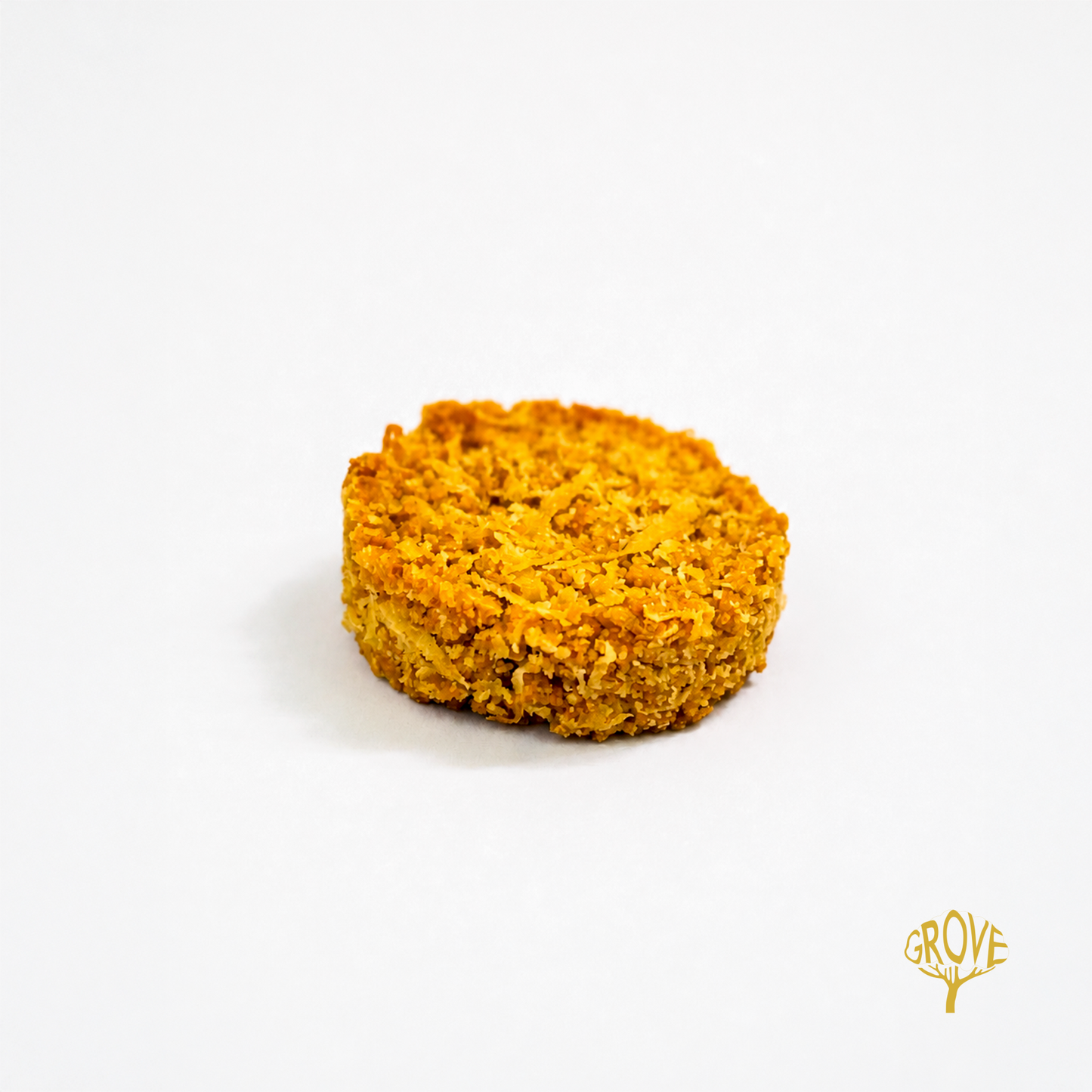 A single round golden-brown textured pet food disc or patty centered on a clean white background, with a small gold GROVE logo in the bottom right corner.